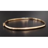 NINE CARAT GOLD BANGLE with cut decoration and with safety clasp, approximately 3.2 grams