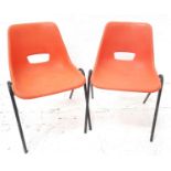 PAIR OF STACKING CHAIRS with orange plastic one piece bodies on black tubular metal frame