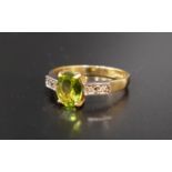 PERIDOT AND DIAMOND RING the central oval cut peridot approximately 1.1cts, flanked by two