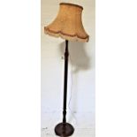 MAHOGANY STANDARD LAMP raised on a circular base with a turned column and shaped tasselled shade,