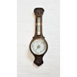 OAK CASED ANEROID BAROMETER with a floral carving above the thermometer, with a circular dial below,