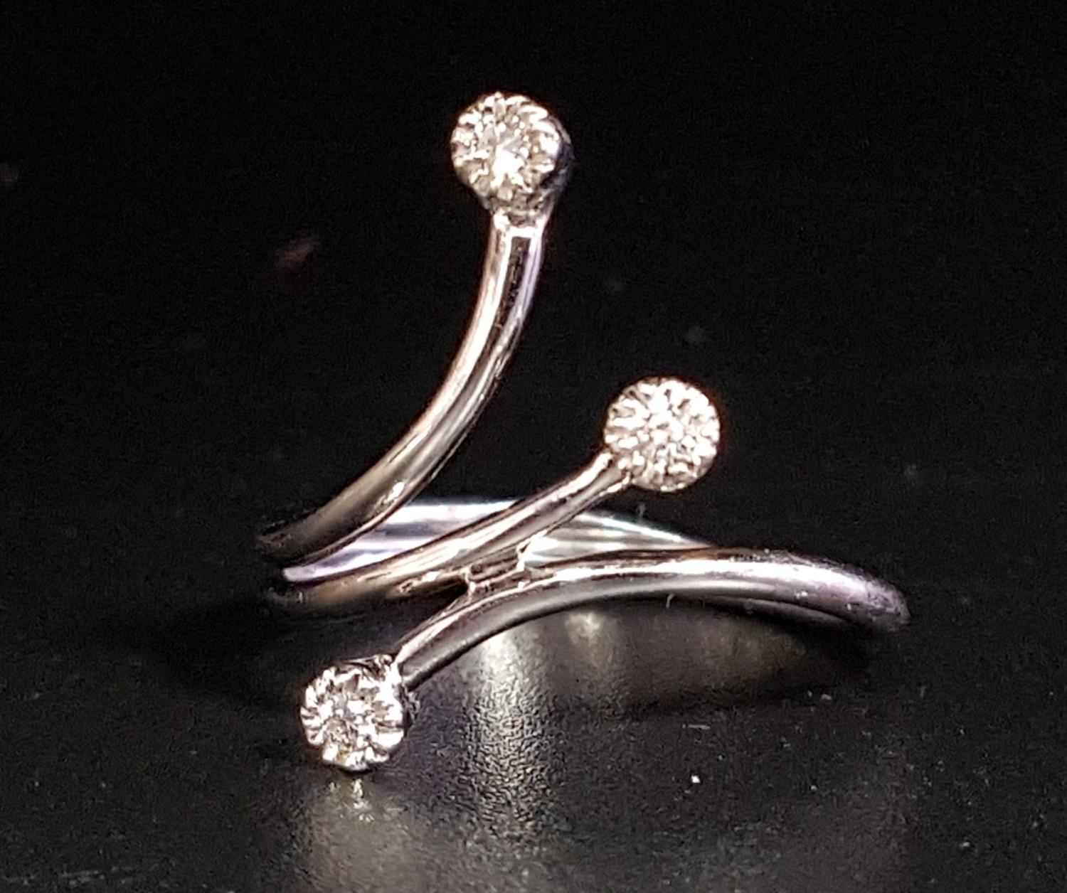 ATTRACTIVE DIAMOND RING formed with three outswept arms, each terminating with a small diamond, in