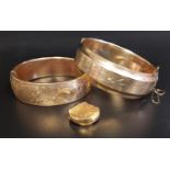 TWO GOLD PLATED HINGED BANGLES both with engraved scroll decoration, one with safety chain; together