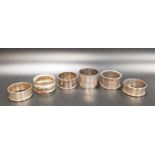 SIX SILVER NAPKIN RINGS of various designs, comprising a pair with engine turned decoration and