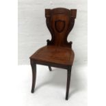 19th CENTURY MAHOGANY HALL CHAIR the carved shaped back centred with a shield, above a shaped