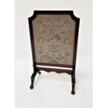 SHAPED MAHOGANY FRAMED FIRE SCREEN with floral needlework panel, standing on splayed claw and ball