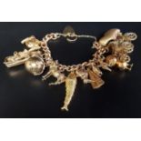 HEAVY NINE CARAT GOLD CHARM BRACELET with a good selection of twelve gold charms, some larger