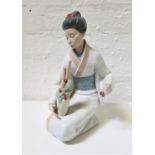 LARGE NAO PORCELAIN FIGURINE of a Geisha kneeling with a vase of flowering bamboo, 34.5cm high