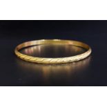 UNMARKED HIGH CARAT GOLD BANGLE testing as 22 carat, with engraved decoration, total weight