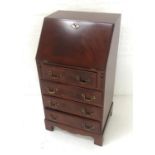 MAHOGANY BUREAU with an inset fall flap and fitted interior above four panelled drawers, standing on