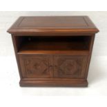 INDONESIAN TEAK SIDE CABINET with a moulded top above a deep recess with a pair of carved panel