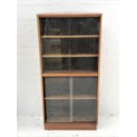 TEAK BOOKCASE with a rectangular moulded top above a pair of sliding glass doors with two adjustable