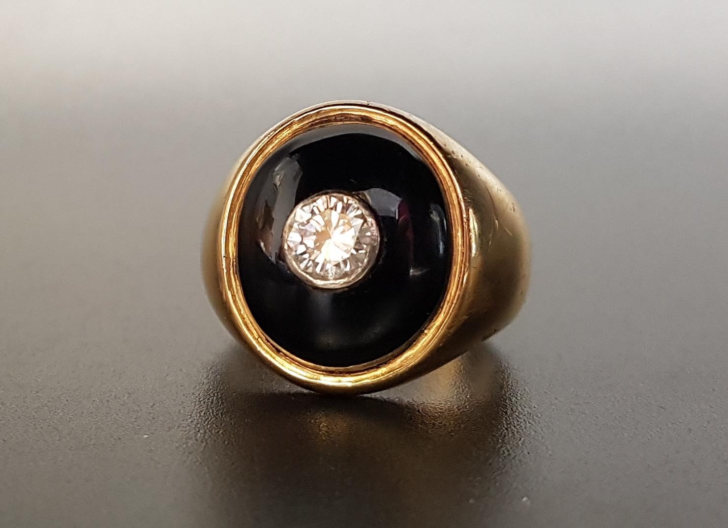 DIAMOND AND ONYX SIGNET RING the central bezel set round brilliant cut diamond approximately 0.