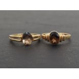 TWO OVAL CUT SMOKY TOPAZ SINGLE STONE RINGS both on nine carat gold shanks, one with decorative
