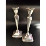 PAIR OF GEORGE V SILVER CANDLESTICKS with angular tapering stems raised on octagonal bases,