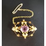 EDWARDIAN AMETHYST AND SEED PEARL BROOCH of pierced oval design, in nine carat gold with safety