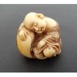 JAPANESE IVORY NETSUKE of a sleeping buddha wearing a decorative robe, 4cm high