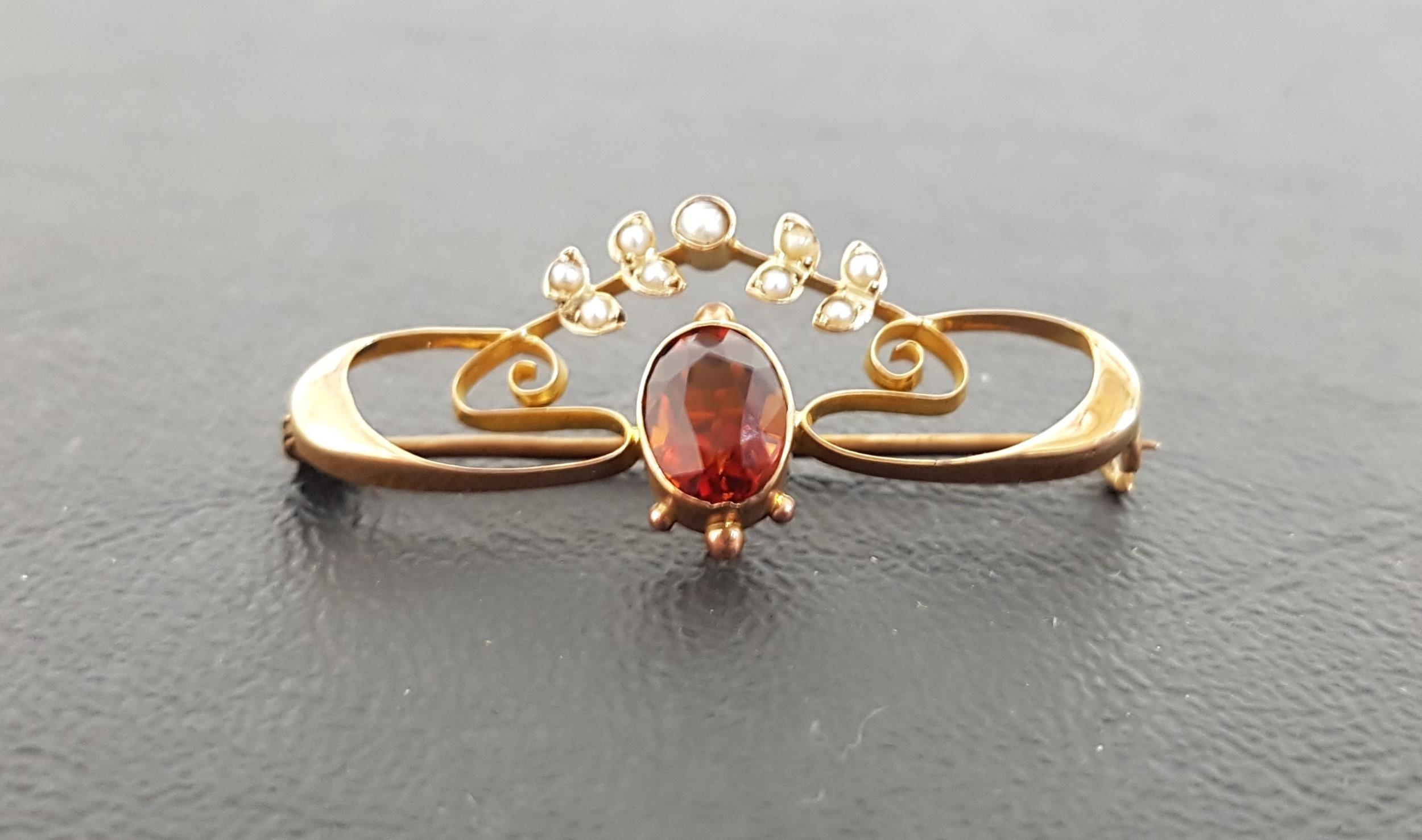 ART NOUVEAU GARNET AND SEED PEARL NINE CARAT GOLD BROOCH the deep orange oval cut garnet above