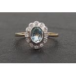 AQUAMARINE AND DIAMOND CLUSTER RING the oval cut aquamarine in twelve diamond surround, on nine