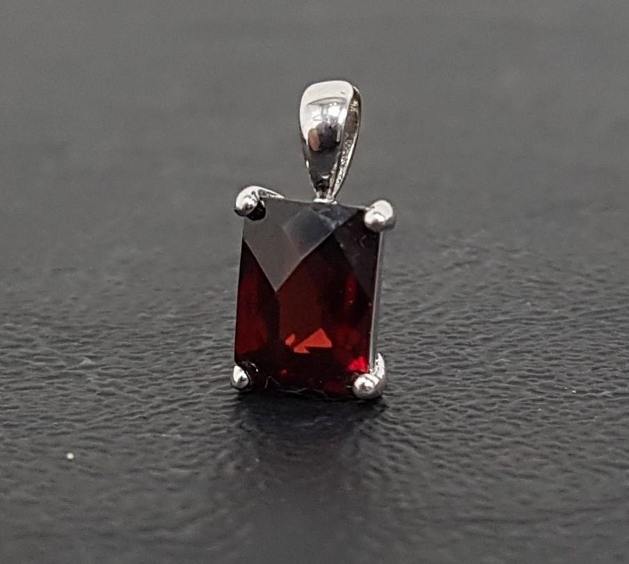 GARNET SINGLE STONE PENDANT the rectangular checkerboard cut garnet in unmarked white gold mount,