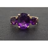 GRADUATED AMETHYST THREE STONE RING the central oval cut amethyst approximately 2.5cts flanked by