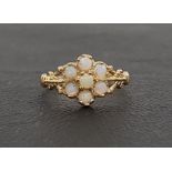 OPAL CLUSTER RING the seven round cabochon opals flanked by shaped and pierced shoulders, on nine
