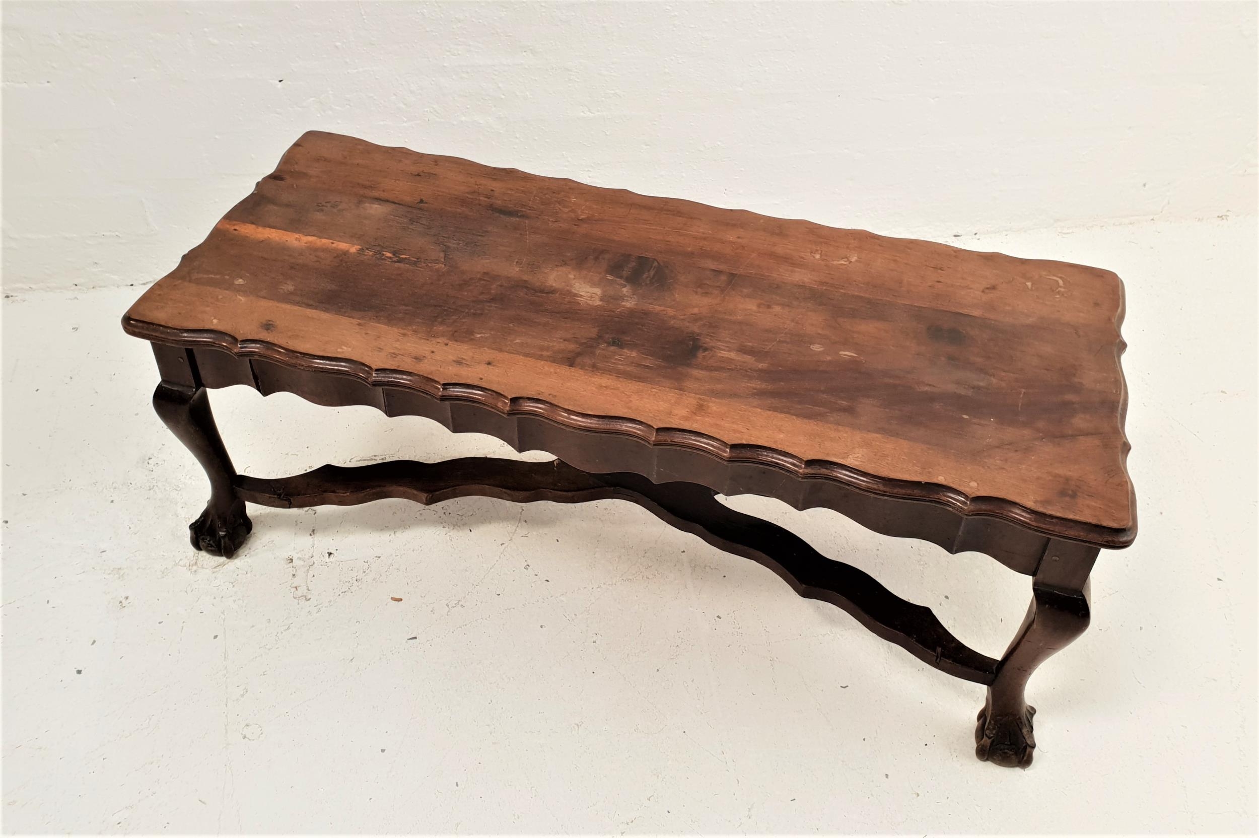 TEAK OCCASIONAL TABLE the oblong top with a wavy edge and frieze, standing on cabriole supports with