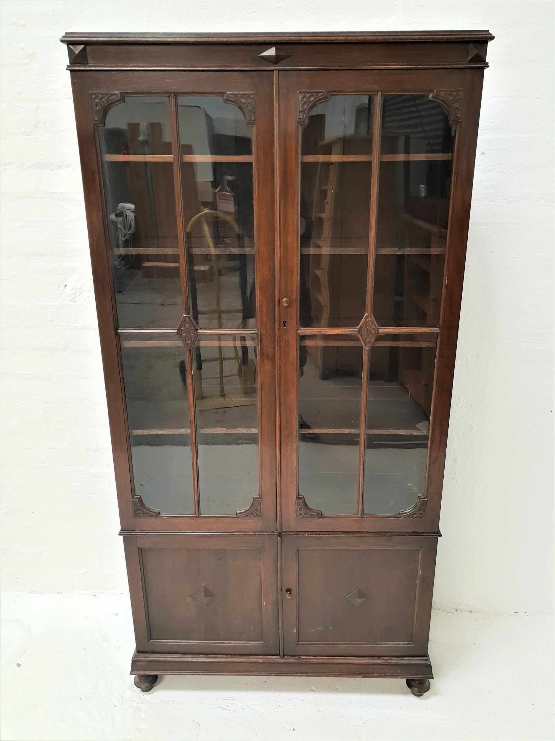 TALL OAK CABINET with a moulded top above a pair of paneled glass doors opening to reveal adjustable
