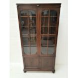 TALL OAK CABINET with a moulded top above a pair of paneled glass doors opening to reveal adjustable