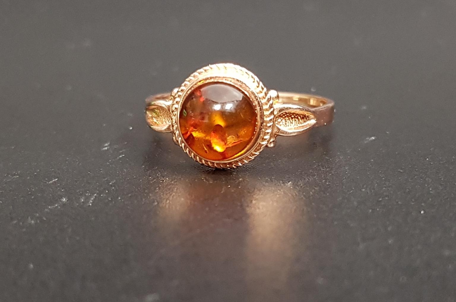 RUSSIAN AMBER SET RING the central round cabochon amber on fourteen carat rose gold shank with