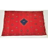 MOROCCAN RUG with a vivid red ground centered with a blue motif and surrounded by geometric