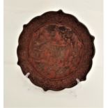 QUING DYNASTY CINNABAR LACQUERED QUADRAFOIL DISH carved in relief depicting figures by a pagoda, the