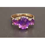 GRADUATED AMETHYST THREE STONE RING the central oval cut amethyst approximately 2.5cts flanked by