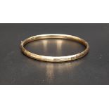 NINE CARAT GOLD HINGED BANGLE with multifaceted decorative surface detail and extending slider