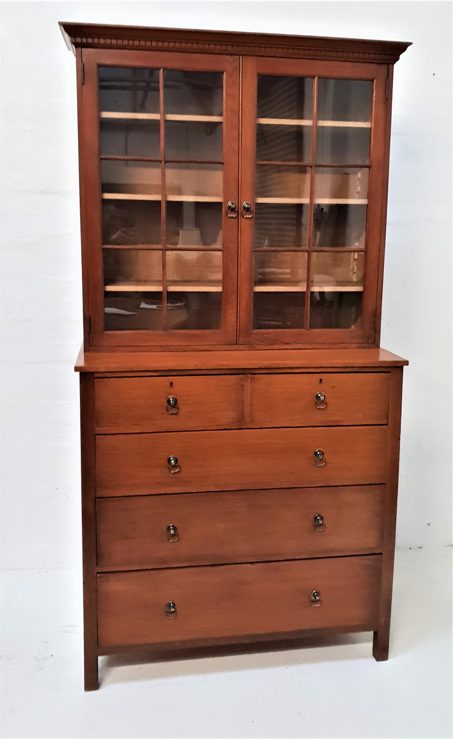 OAK BOOKCASE ON CHEST with a moulded dentil cornice above a pair of glass panelled doors opening