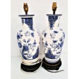 PAIR OF DUTCH BLUE AND WHITE CHINA LAMPS decorated with flowers, on carved circular wooden bases,