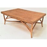 LARGE CANED OCCASIONAL TABLE with an oblong top standing on shaped supports united by a stretcher,