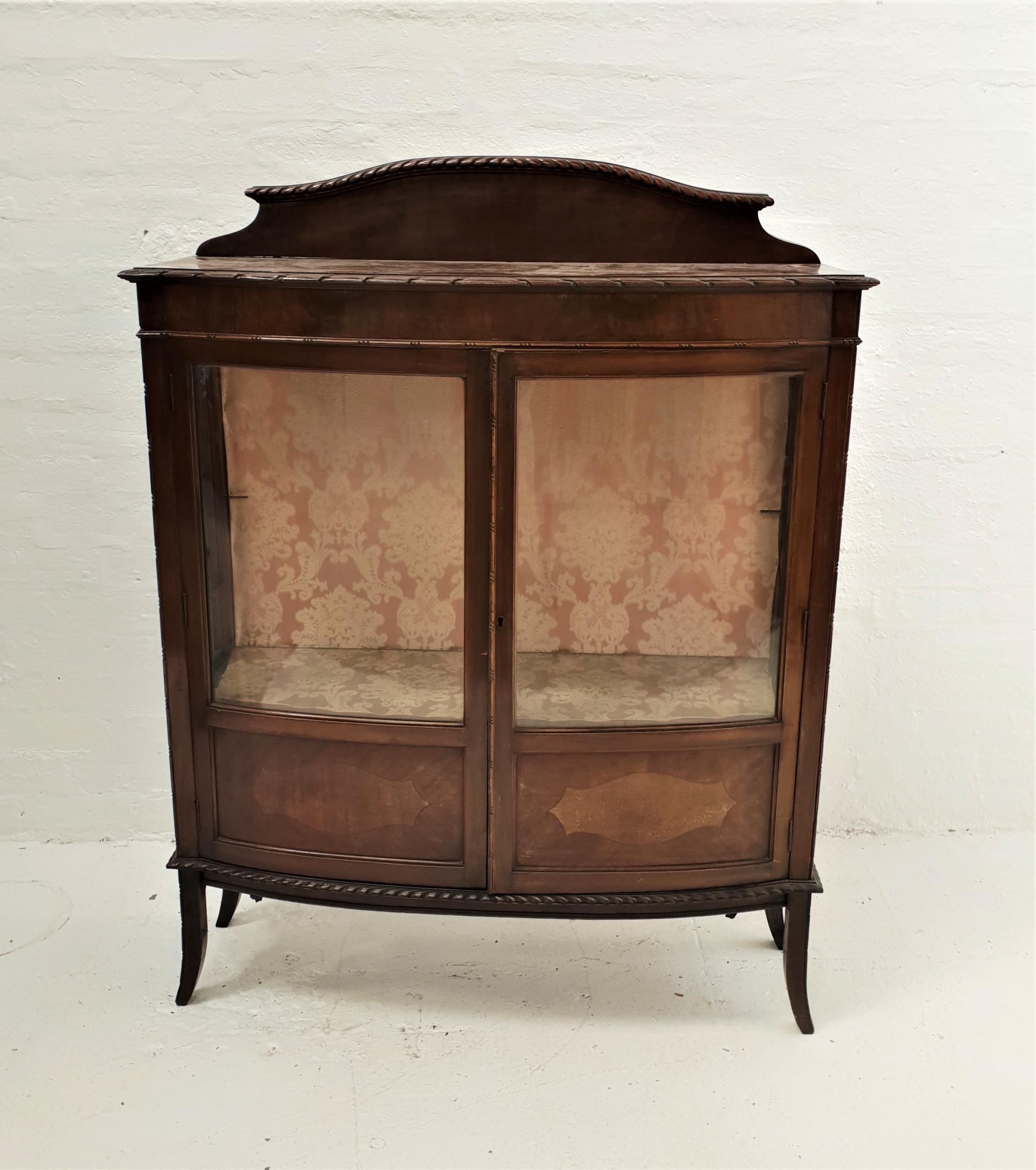 BOW FRONT MAHOGANY DISPLAY CABINET with a shaped raised back above a moulded top, the part glazed
