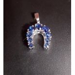 GRADUATED SAPPHIRE SET HORSESHOE PENDANT in eight carat white gold, marked '333', approximately 1.