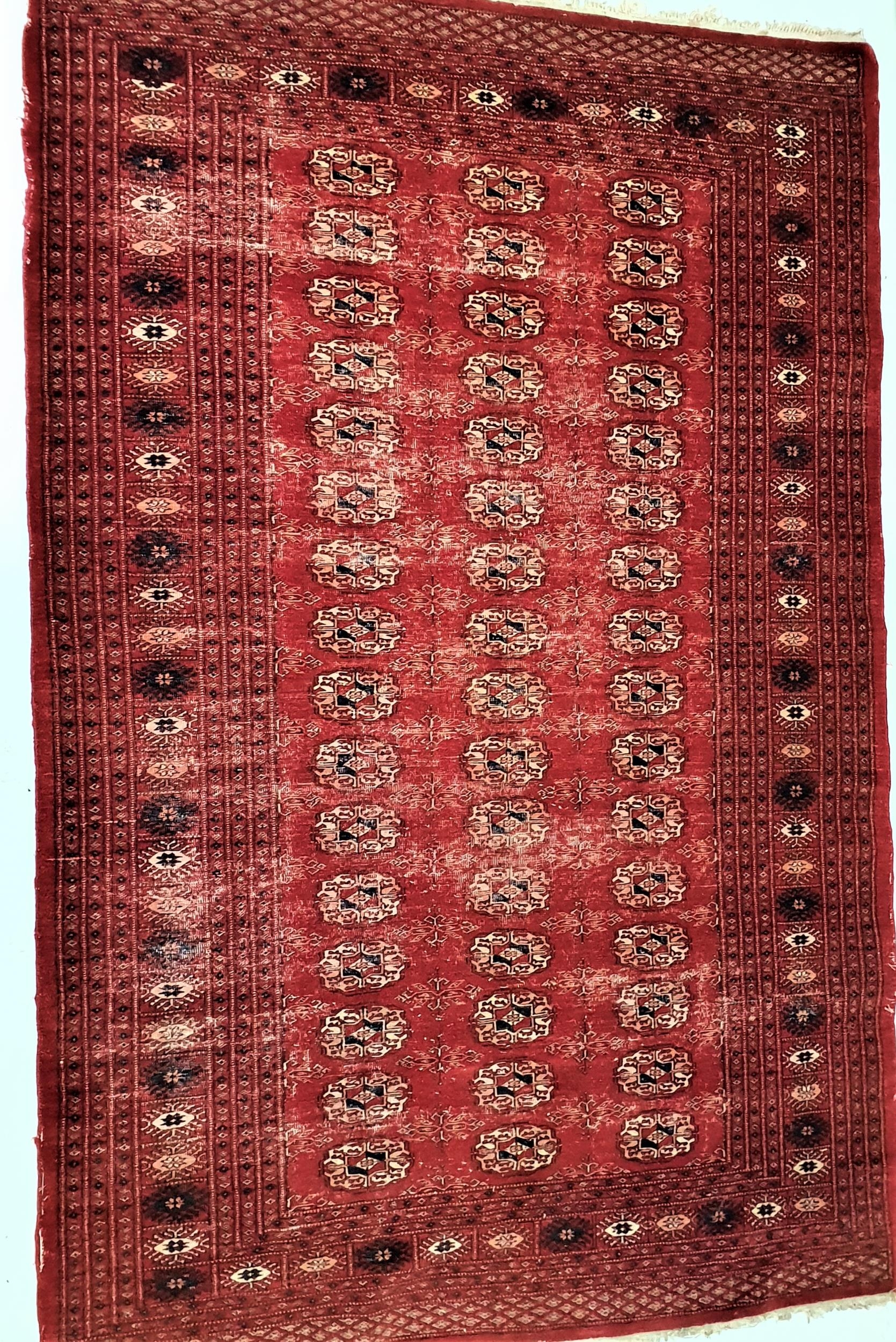 BOKHARA RUG with a deep red ground, the central section with geometric motifs, encased by a multi