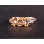 CERTIFIED PRETO IMPERIAL TOPAZ AND WHITE ZIRCON RING on nine carat rose gold shank, the three oval