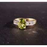 PERIDOT AND DIAMOND RING the central oval cut peridot approximately 1ct flanked by two diamonds to