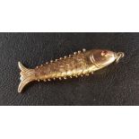 FOURTEEN CARAT GOLD ARTICULATED FISH PENDANT with engraved scale detail and red glass eyes,