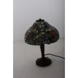 A TIFFANY DESIGN BRONZED TABLE LAMP the multicoloured mushroom shaped shade above a reeded column on