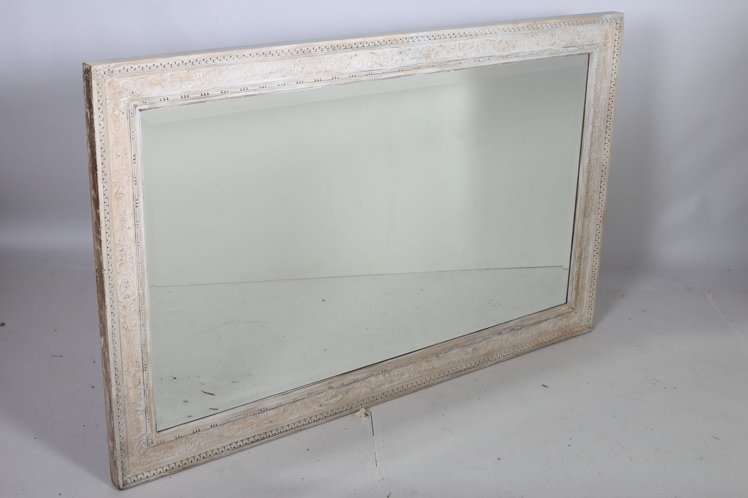 A CONTINENTAL CREAM PAINTED MIRROR the rectangular bevelled glass plate within a C-scroll flowerhead