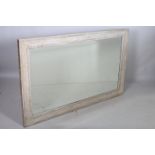 A CONTINENTAL CREAM PAINTED MIRROR the rectangular bevelled glass plate within a C-scroll flowerhead