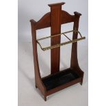 AN EDWARDIAN MAHOGANY AND BRASS THREE COMPARTMENT STICK STAND of rectangular outline with linen fold