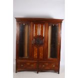 AN EDWARDIAN MAHOGANY AND WALNUT THREE DOOR WARDROBE the moulded cornice above a carved and