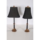 A PAIR OF CONTINENTAL EBONISED AND GILT TABLE LAMPS each with a Corinthian capital on reeded triform