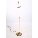 A BRASS FLOOR STANDING LAMP with adjustable arm above a cylindrical column on a circular spreading